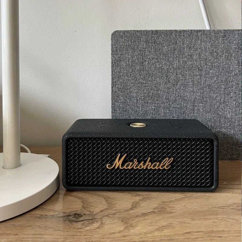 Marshall speaker on a wooden surface with a lamp and textured wall in the background