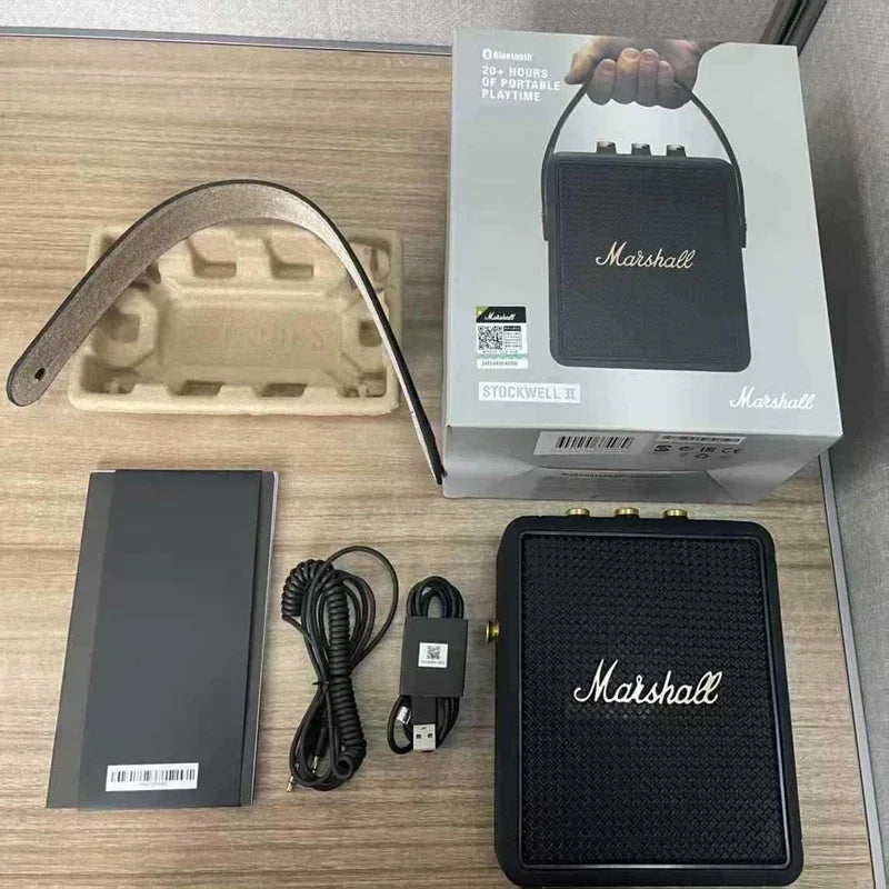 Marshall portable speaker with packaging, manual, and cable on a wooden surface