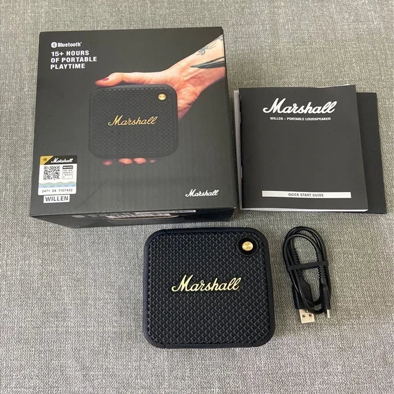 Marshall speaker with packaging, user manual, and cable on a gray surface