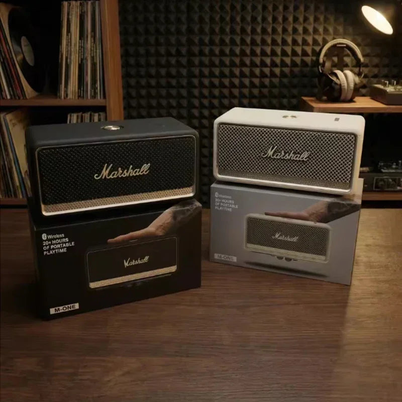 Marshall speakers and their packaging on a wooden surface with a bookshelf in the background.
