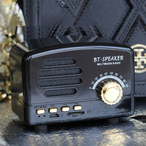 Black BT-speaker multimedia radio with gold knob on a reflective surface